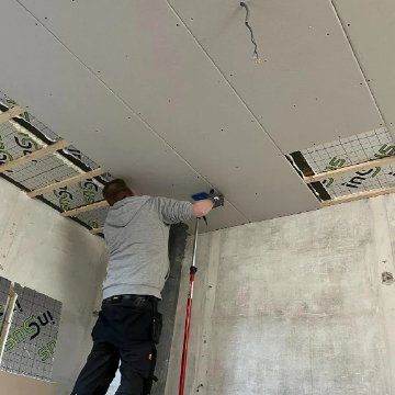 Monteur werkt aan een geïsoleerd plafond met gipsplaten